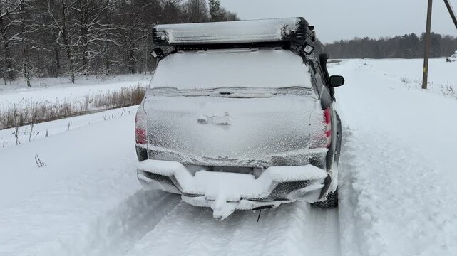 A car covered in snow on a snowy road outside the city.