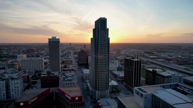 Aerial view of downtown skyscrapers basking in the warm glow of the setting sun, casting long shadows across the silent streets, Omaha, Nebraska, United States.