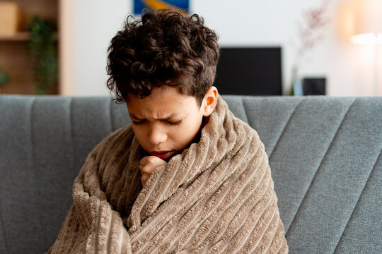 Sick boy suffering from cold and flu at home, having a cough and feeling unwell