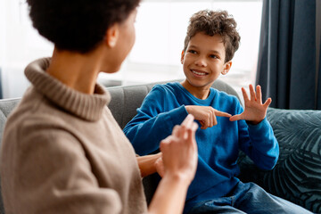 Boy learning sign language with a woman, communicating with hand gestures © Maria Vitkovska