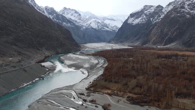 Aerial view of a winding river contrasting with the stark mountains and sparse vegetation, creating a dramatic landscape, Daghoni Balgar, Gilgit Baltistan, Pakistan.