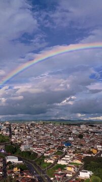 Arco-&iacute;ris completo com a paisagem urbana de Varginha, Minas Gerais