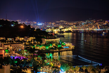 Obraz premium Vibrant nightscape of coastal city with illuminated waterfront and skyline