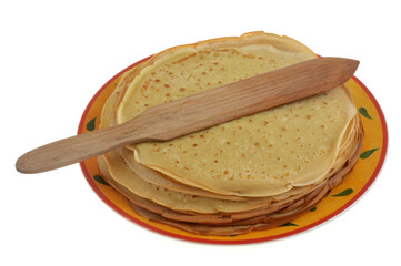 Cr&ecirc;pes bretonnes empil&eacute;es dans une assiette avec une spatule en bois en gros plan isol&eacute;es sur fond blanc