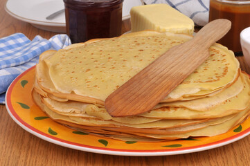 Assiette de cr&ecirc;pes bretonnes avec une spatule en bois, du beurre, de la confiture et du caramel