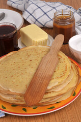 Assiette de cr&ecirc;pes bretonnes avec une spatule en bois, du beurre, du sucre, de la confiture et du caramel