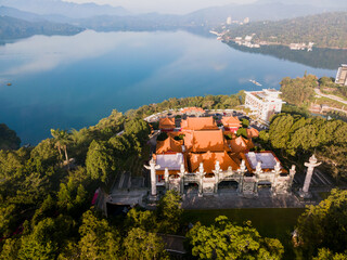 Aerial view of Wen Wu Temple overlooking Sun Moon Lake in Taiwan on a sunny morning, with traditional Chinese architecture set against blue water, forested hills, and clear skies.

