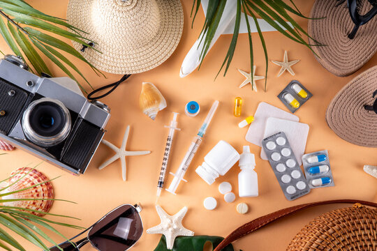 Summer holiday travel setup background including first aid kit with medications, pills, hat, and vacation accessories. Medication in journey, vaccinations, travel health insurance concept