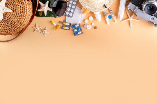 Summer holiday travel setup background including first aid kit with medications, pills, hat, and vacation accessories. Medication in journey, vaccinations, travel health insurance concept