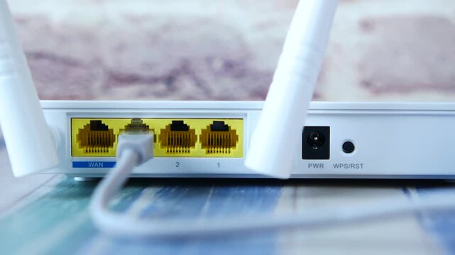 Close up of wifi router back panel with ethernet cable plugged in showing wan and lan ports
