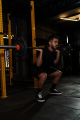 Strong Athletic Man Performing Barbell Back Squat in Modern Gym