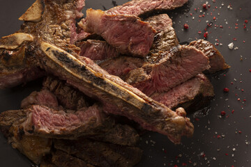 Thick ribeye steak with exposed bone and smoky crust, juicy pink center and coarse seasoning butcherstyle presentation with embers and charcoal tones for bold, hearty meal imagery.