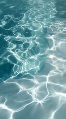 Sunlight reflects on the surface of clear blue water, creating intricate patterns and ripples. The bright light dances across the gentle waves, forming a serene and calming atmosphere