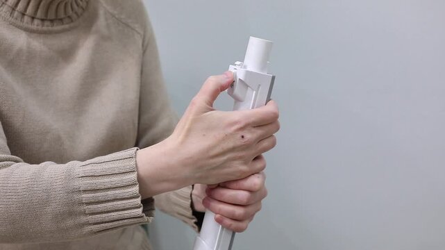 Clicks and creaks of the latch on the tube of a handheld corded vacuum cleaner