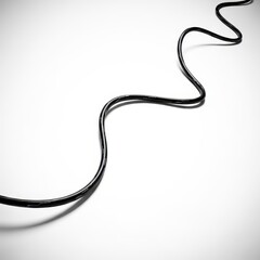 Fototapeta premium A sharp image of a flexible black insulated electrical wire cable snaking or coiling dramatically against a bright white backdrop surface, conductor, winding, shape