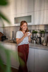 Woman enjoying morning coffee in modern kitchen