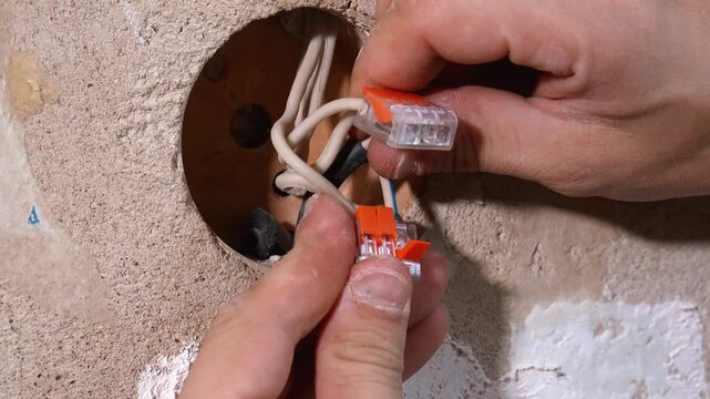 Wires neatly connected. Installer handles electrical cables with precision. detailed overview of the wiring process with focus on safety and correct connections inside the junction box with terminals