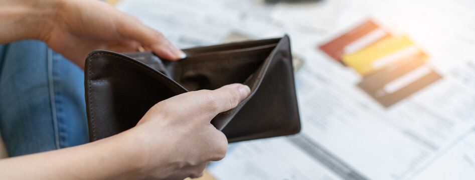 Bankrupt people concept. Close-up view of the hands of a young woman opening an empty wallet on the payday of credit card bills
