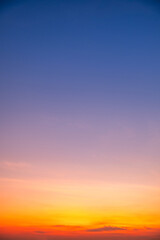 Fototapeta premium Beautiful sunrise sky with vibrant gradient orange and gold colors and soft blue, Clear atmosphere with wispy clouds. Peaceful, perfect for background and copy space, High resolution images Vertical