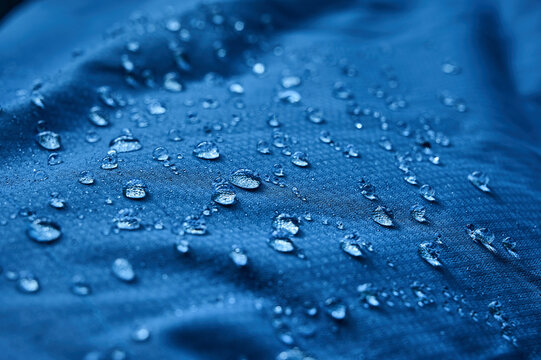 Water drops on waterproof membrane fabric. Detail view of texture of blue waterproof cloth.