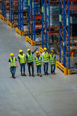 Fototapeta premium Group of warehouse workers in safety vests and helmets inspecting storage racks