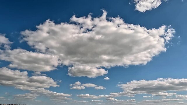 Flowing forward fluffy clouds in the blue skies. 4K video (Ultra High Definition) of cloudscape. Sky and clouds Timelapse. Sun shines through the clouds on the blue sky background.