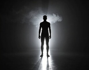 Obraz premium Silhouette of a Man Standing Alone in a Dark Foggy Environment