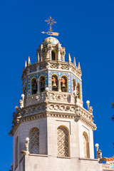 Obraz premium Ornate Spanish-Moor bell tower against blue sky with mosaics, gargoyles, bells, spires