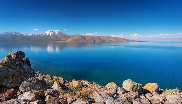 Tranquil Landscape Of Lake Sevan Armenia Seen From A Rocky Hillside The Deep Blue Water Reflects The Sky Surrounded By Distant Brown Mountains