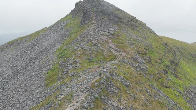 Aerial, forward drone flight above hiking trail on Hesten mountain, the neighbour mountain from famous Segla on Senja island. Amazing hiking destination, outdoor adventure. Some hikers on the trail.