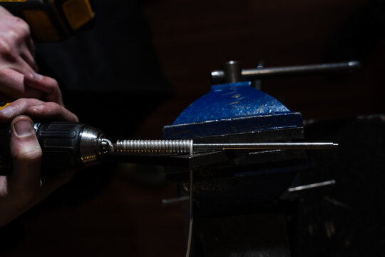 Jeweler coiling metal wire onto mandrel to prepare chain links.