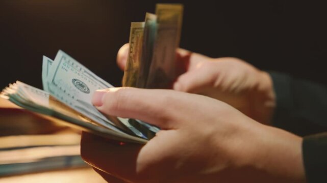 silhouette person counting money, close-up man hands holding stack of dollar bills. Concept fraud counts cash for profit laundering investment scam bribe corruption. night dark room. high tax dues 4k