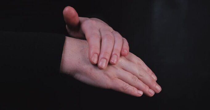 Adult woman applying cream on her hands, focusing on mature skin care, sun spots, anti-aging, and overall skin wellness.