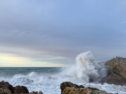 Turquoise water, giant foamy wave crashing on rocky coast, Atlantic Ocean