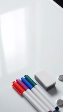 Colorful markers and an eraser are neatly arranged on a clean whiteboard. Small magnets complete the essential tools for presentations or learning.