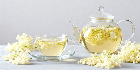 Glass teacup and teapot filled with elderflower herbal tea