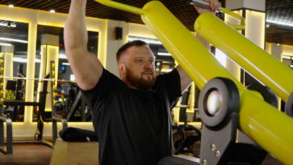 Strong man exercising on shoulder press machine in gym