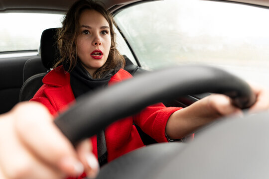Terrified female driver a second before the accident. young, pretty, woman holds the steering wheel of car. Frightened Lady girl who is owner or rent a car for travel