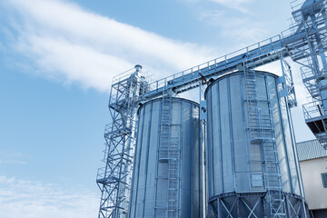 Modern steel grain silos in agricultural complex against blue sky