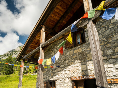 Stone building, Tragonia hut, with wooden beams and colorful prayer flags,  Tragonia hut. Tragonia hut,Forni di Sopra,Dolomites,Italy