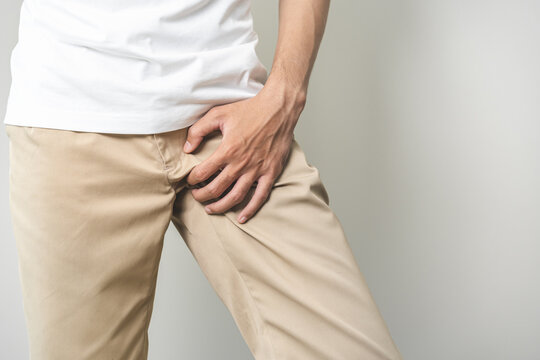 Closeup annoying itch asian man with an itchy his jock and butt, male scratching crotch with his hand, itching groin, male suffering body problem. Health care, hygiene, skin disease, medicine concept.