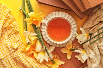 Cozy spring morning with daffodils, tea, and a book, evoking warmth and relaxation