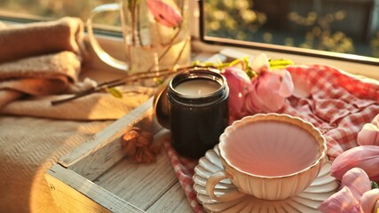 Cozy morning tea with blooming magnolia flowers and a scented candle by the window