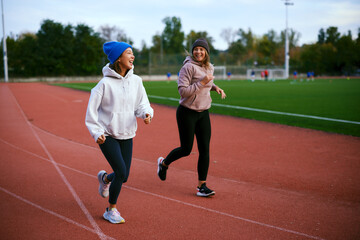 Obraz premium Female friends jogging together and talking on running track