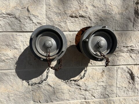 Fire Department Connection FDC Double Storz Inlets with Protective Dust Caps and Chains on Exterior Stone Wall Facade, Emergency Water Supply System for Firefighting and Building Safety Infrastructure