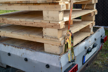 Trailer with wooden Euro pallets and a tension strap for safety.
