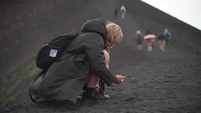 Woman hiker collecting volcanic rock on mount etna
