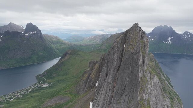 Aerial, slow forward drone flight impressive Segla mountain peak,  famous Hesten mountain on Senja island during cloudy summer day. Fjordgard village in distance. Amazing hiking destination, outdoor a