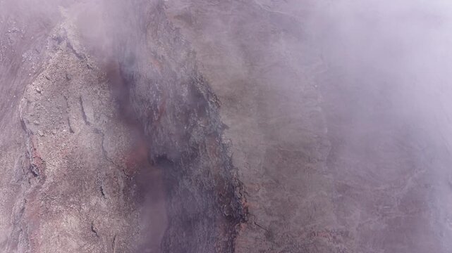 Drone footage with a gentle forward movement and upward tilt over Dolomieu Crater at Piton de la Fournaise on Reunion Island.