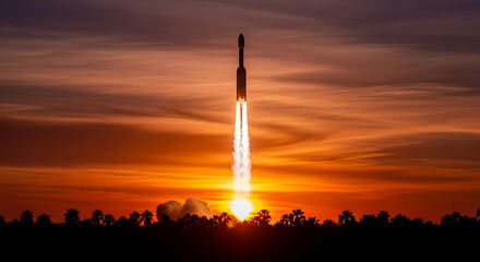 Obraz premium Rocket Launch at Sunset with Fiery Exhaust and Silhouetted Trees against a Vibrant Sky